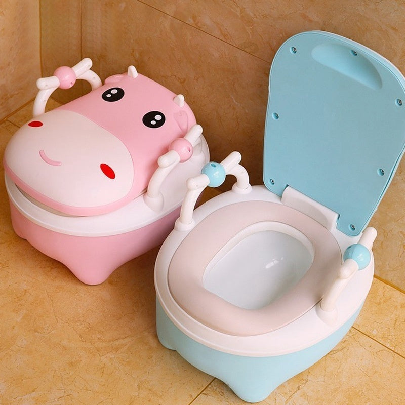 Two cow-themed potty chairs for toddlers, one in pink and one in blue, each with a soft seat cover and a closed lid.