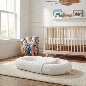 White baby wrap on a rug in a nursery with a crib and toys in the background