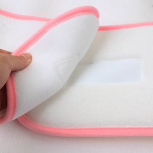 White fabric with pink trim held by a hand on a white background
