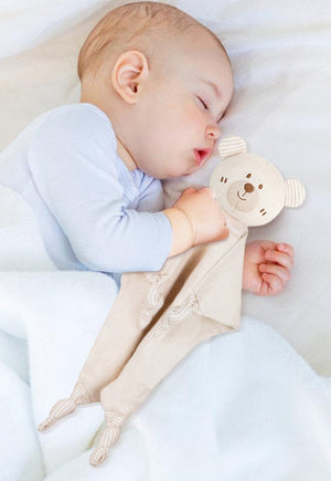 Baby sleeping with a soft toy, surrounded by organic cotton soothing towel.