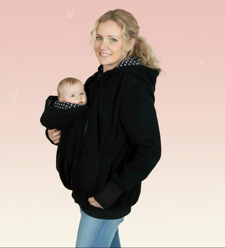 Woman wearing a black hoodie with a baby carrier on a white background
