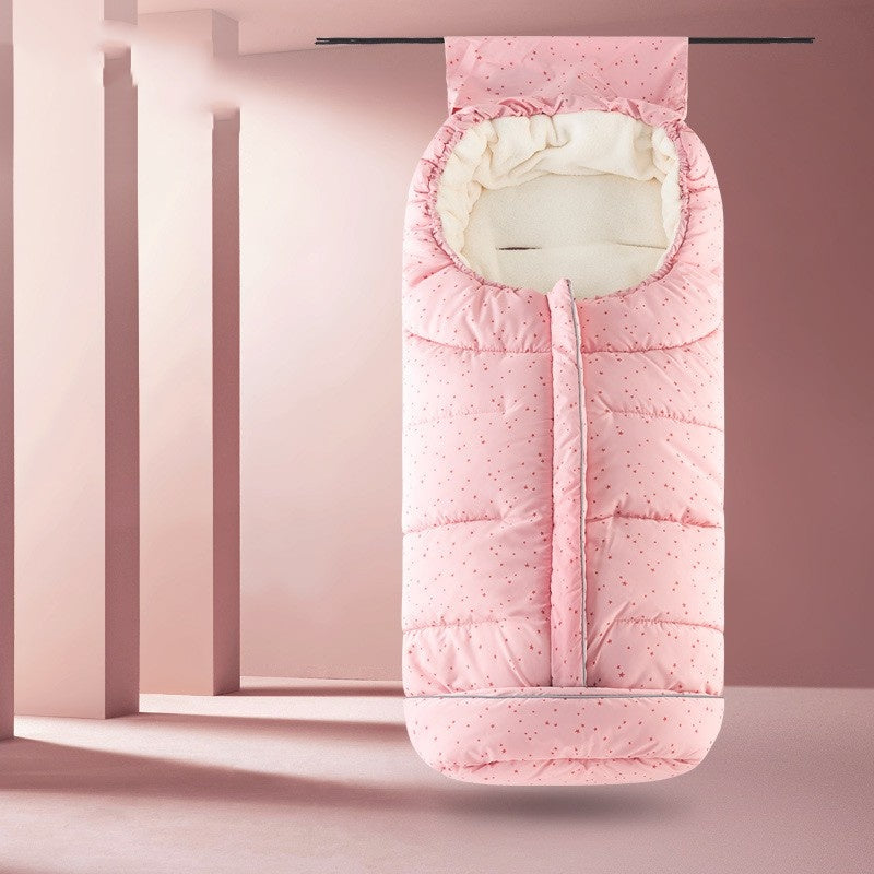 A pink baby sleeping bag with a subtle polka dot pattern and a cream-colored lining, hanging from a black rod against a minimalist pink background.