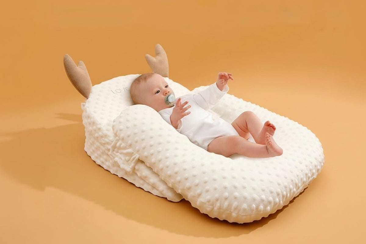Baby lying on a white pillow with antler-like decorations against an orange background