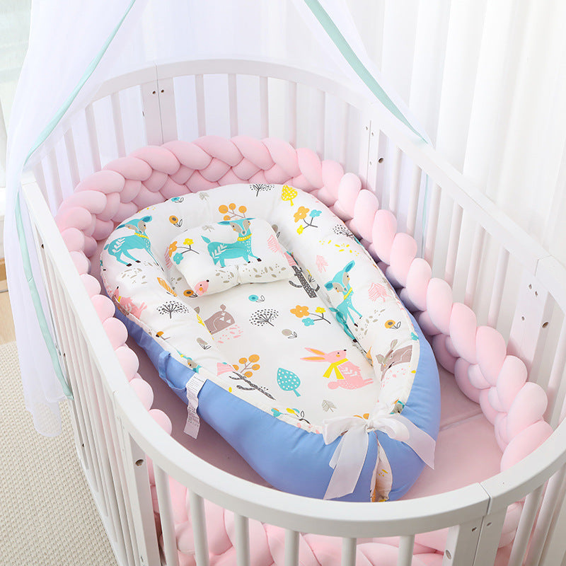 Baby crib with a colorful baby nest and pink bumper pad.