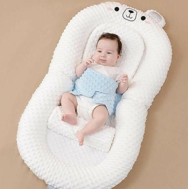 A newborn infant baby lounger bed in pink color, designed with anti-reflux and anti-colic features, including a folding bed in bed mode and an anti-spill milk out feature.