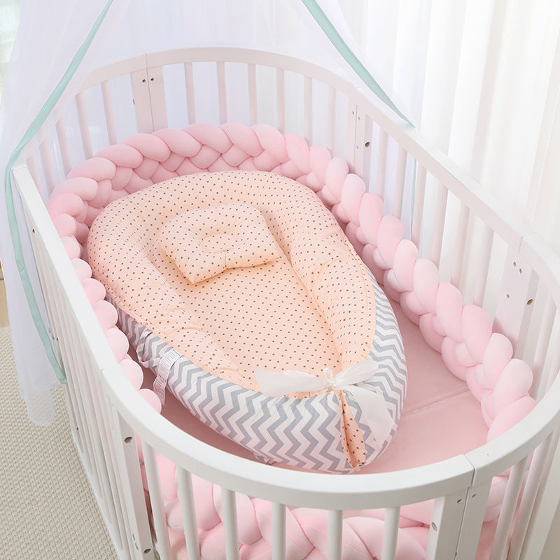 Baby crib with pink and white bumper and soft blanket