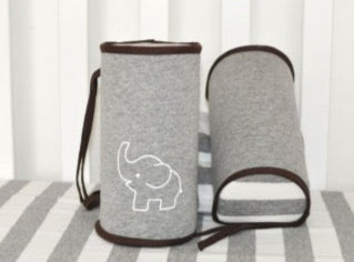 A baby lying on a safety support pillow designed to prevent rolling over, featuring gray color with red trim and a white embroidered design.