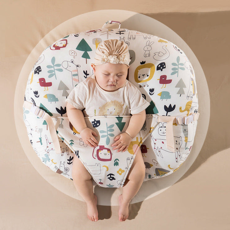 A baby lying on an inclined anti-roll and anti-spit-up pillow with a colorful animal pattern.