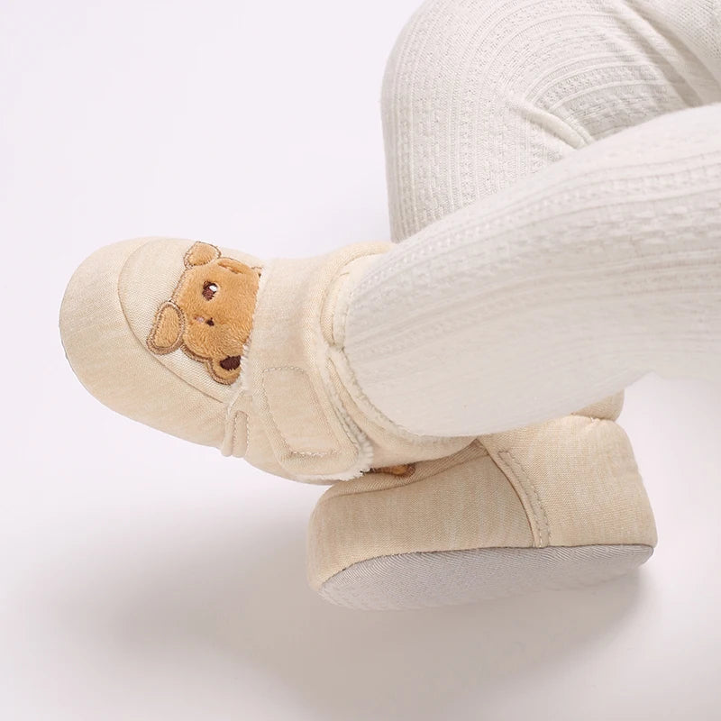 Beige slippers with a teddy bear design on a white background