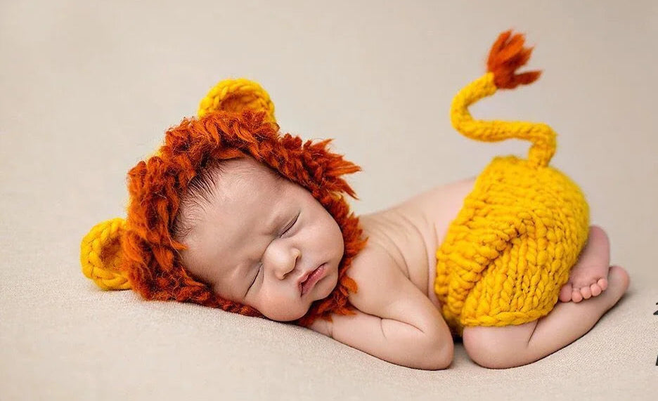 Newborn baby wearing a lion costume with a 2-pack label on a beige background