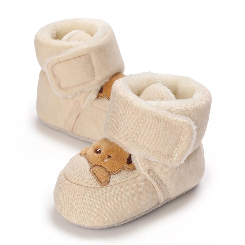 Pair of cream-colored baby booties with bear faces on a white background