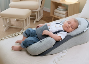 Child sleeping on a cushioned support in a cozy room with a chair and nightstand.