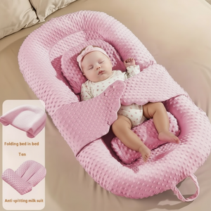 Baby sleeping in a pink baby nest on a bed