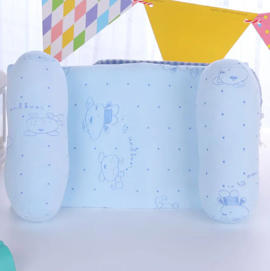 A newborn baby lying on a gray anti-roll safety support pillow with red trim.