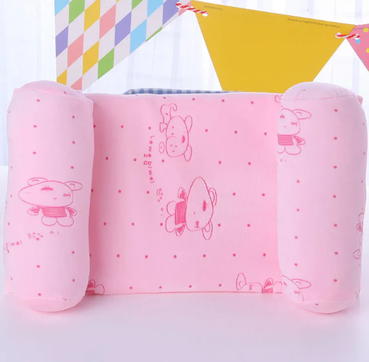 A newborn baby lying on a gray anti-roll safety support pillow with red trim.