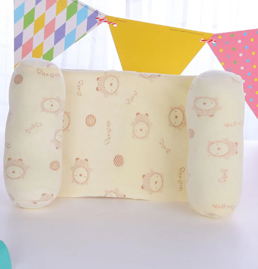 A newborn baby lying on a gray anti-roll safety support pillow with red trim.