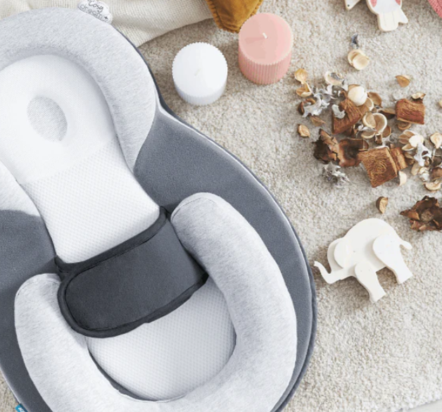 Gray and white neck pillow on a textured surface with decorative items