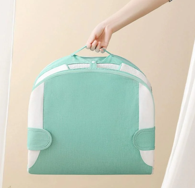 Green garment bag held by a hand against a beige background