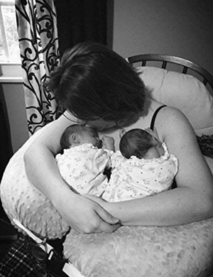 Black and white photo of a woman holding two babies in a basket.