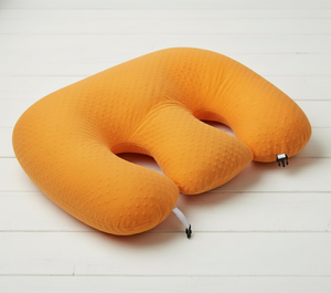Orange travel neck pillow on a white wooden floor