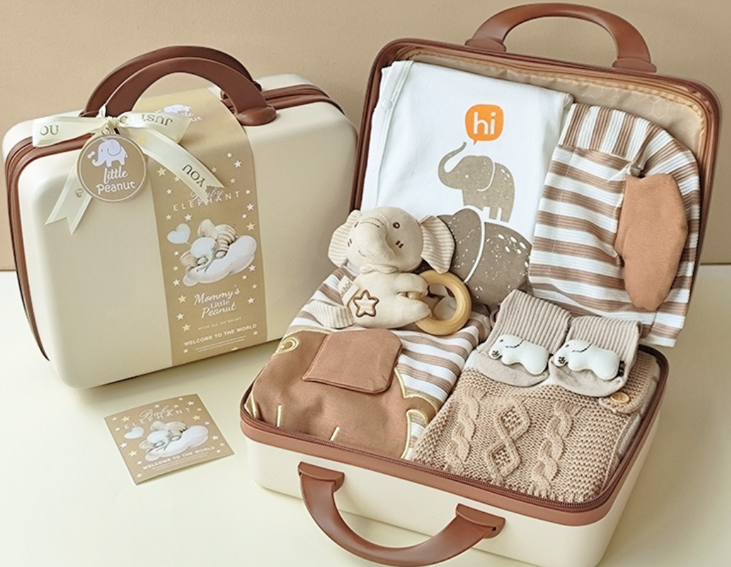Baby gift set with toys and clothes in a suitcase on a beige background