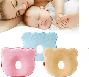 Baby sleeping with a woman, with two baby pillows, one pink and one blue, displayed below.