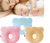 Baby sleeping with a woman, with two baby pillows, one pink and one blue, displayed below.