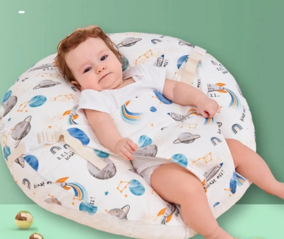 Baby lying on a soft, patterned cushion against a green background