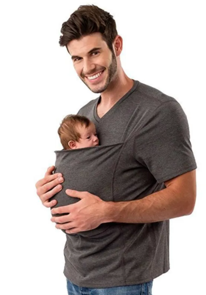Man holding a baby in a gray baby carrier against a white background