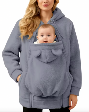 Person wearing a gray baby carrier with a baby inside on a white background