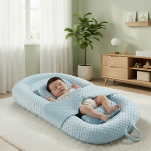Baby lying in a blue waffle-textured baby nest in a nursery setting.