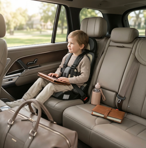 Child in a car seat using a tablet in a vehicle interior.