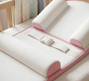 White and pink baby crib mattress with rolled-up sides on a crib