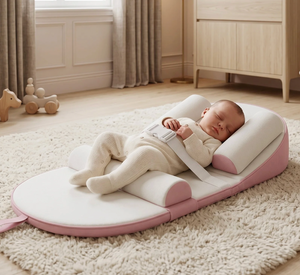 Baby lying on a pink and white safety cushion in a nursery.