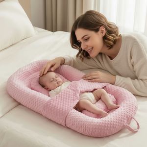 Woman with a baby in a pink baby nest on a couch