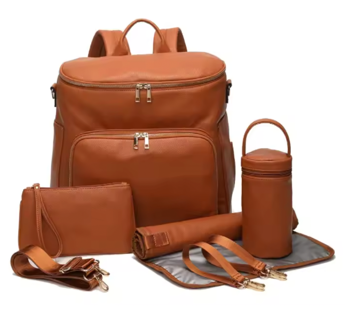A tan faux-leather multi-piece diaper bag set with a main backpack, matching pouch, cylindrical bottle holder, rolled mat, and detachable shoulder strap, displayed on a white background.