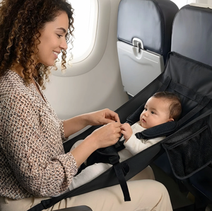 Woman securing a baby in an airplane seat with a car seat
