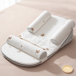 A baby burping pillow set with a quilted white mattress, two upright pillow supports, and two side headrests, decorated with small teddy bear faces. The set is displayed on a beige background with text overlays describing its features.