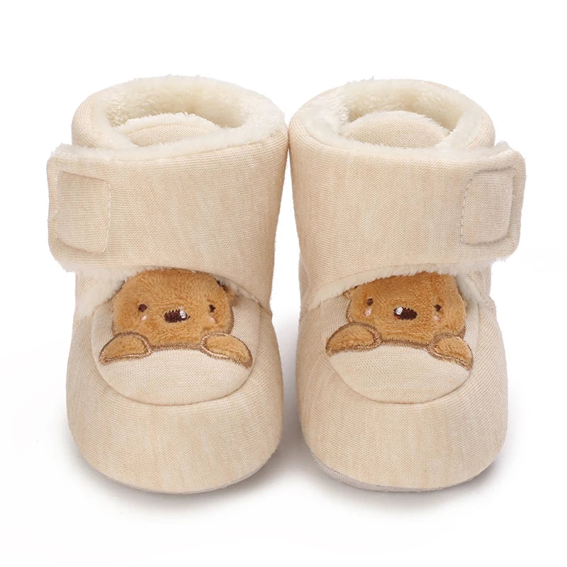 Beige baby booties with bear face design on a white background