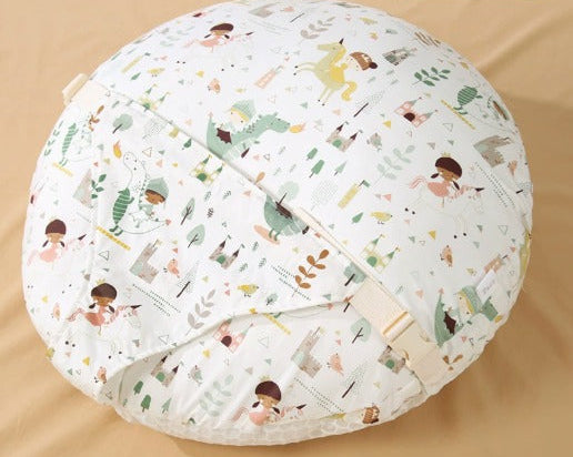 A round, quilted baby support pillow with a white background and a colorful cartoon dinosaur and child pattern, shown on a beige fabric background with a Chinese text label in the top right corner.