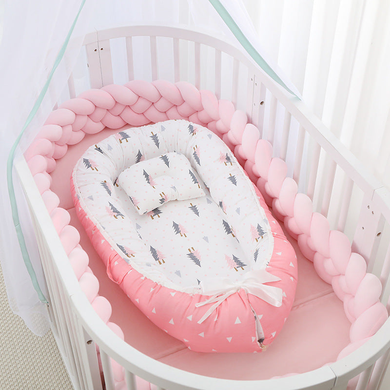 Baby crib with pink bumper and white mattress with animal pattern