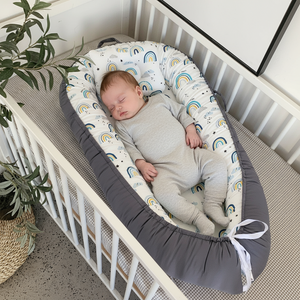 Baby sleeping in a crib with a soft, patterned bumper