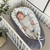 Baby sleeping in a crib with a soft, patterned bumper
