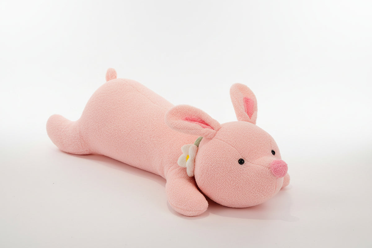 Pink plush toy resembling a rabbit on a textured surface