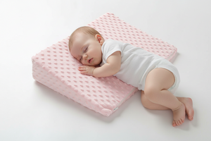 Baby sleeping on a pink textured pillow against a white background