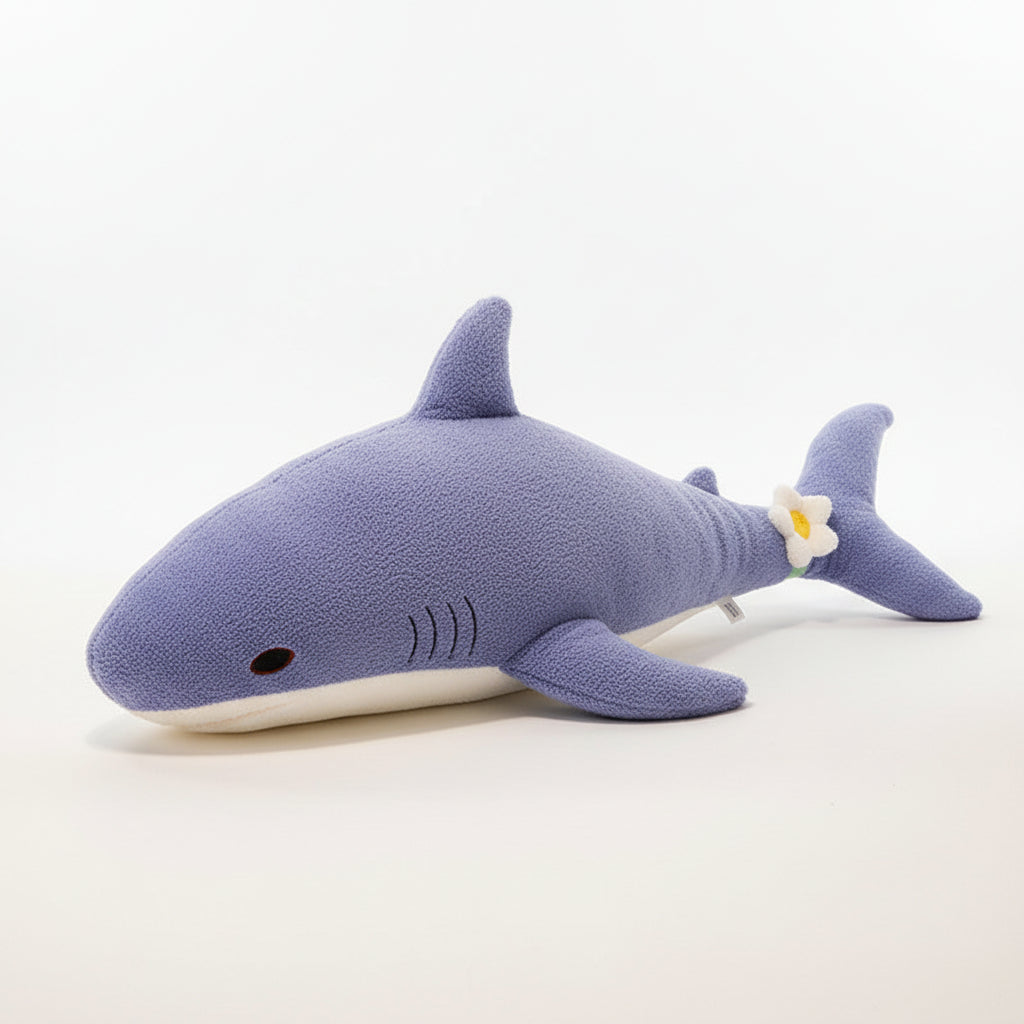 Blue shark-shaped pillow on a bed with a wooden headboard and decorative items in the background.