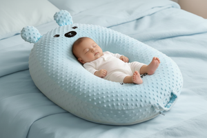 Baby sleeping in a blue bear-shaped pillow on a beige surface
