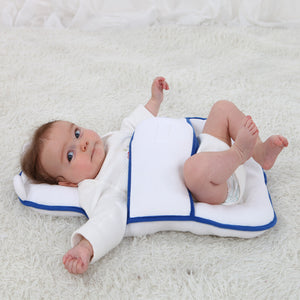 Baby lying on a white cushion with blue trim on a white surface