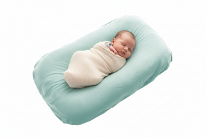 Newborn baby wrapped in a blanket lying on a green baby lounger pillow against a white background