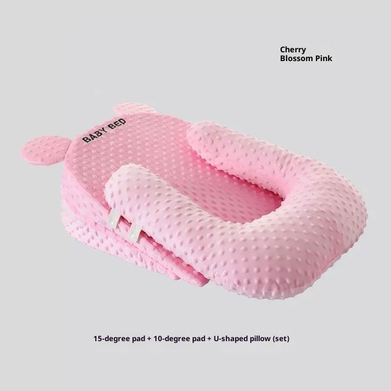 Pink baby nest with U-shaped pillow on a light gray background